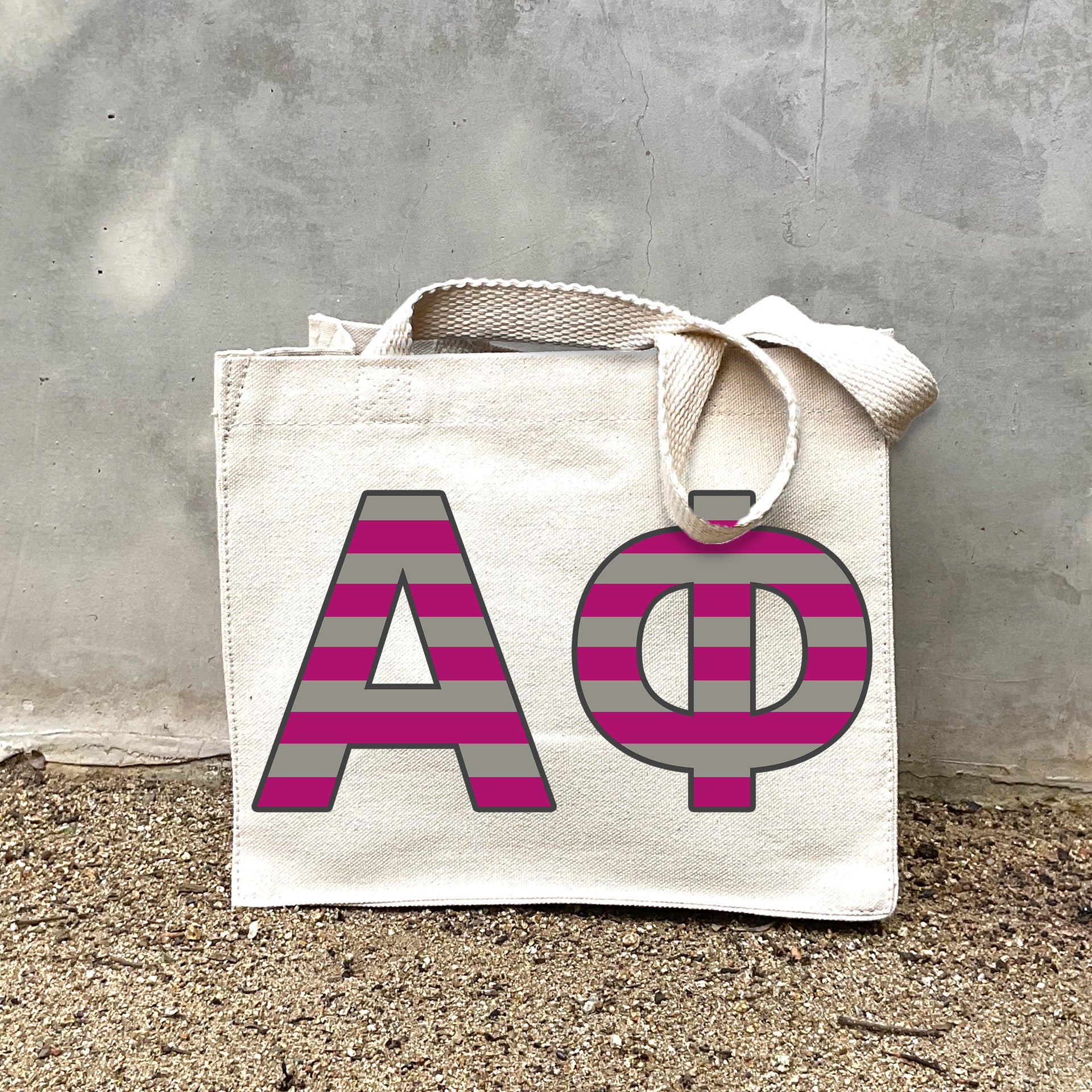 Model carrying the Alpha Phi Greek letters in sorority colors small striped tote.