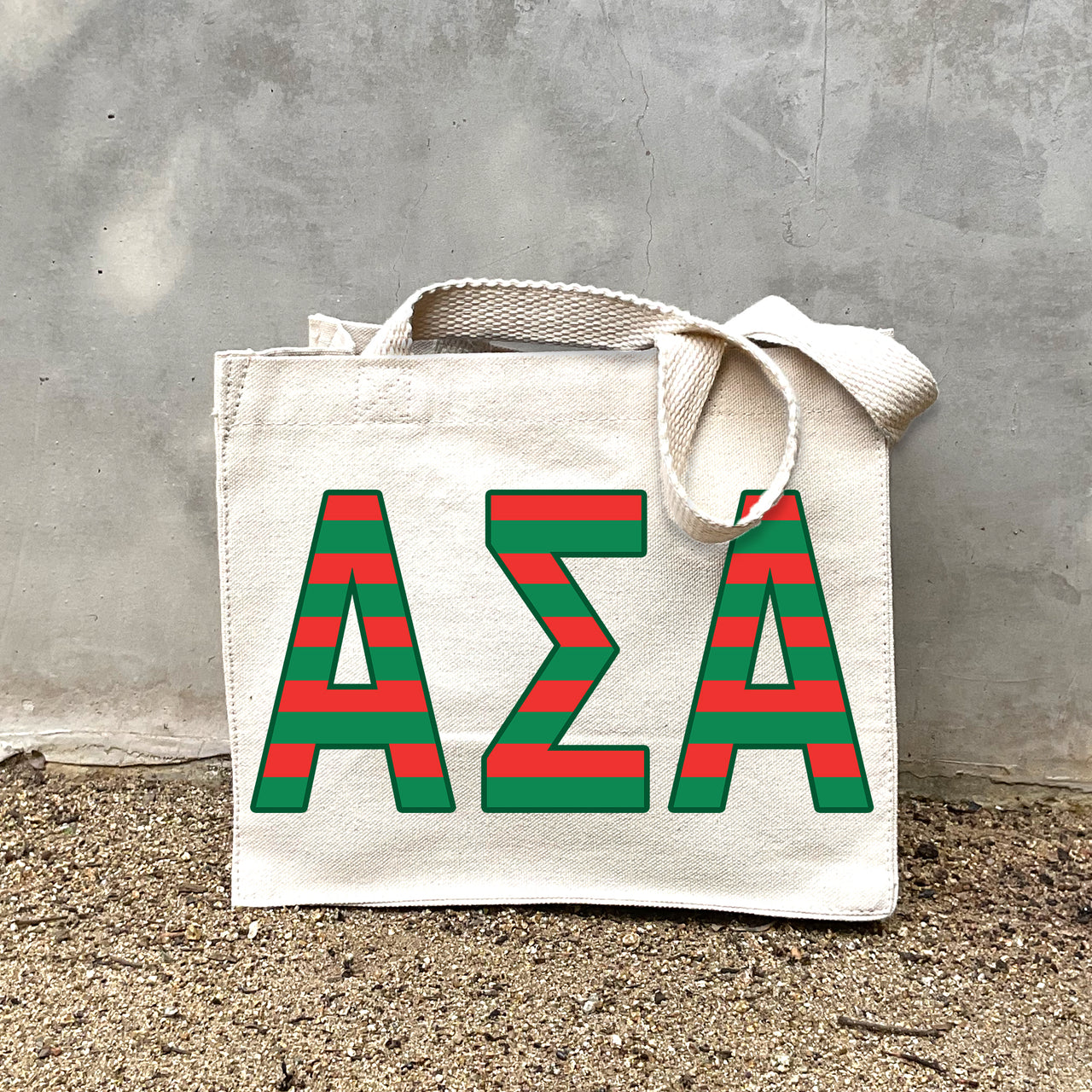 Model carrying the Alpha Sigma Alpha Greek letters in sorority colors small striped tote.