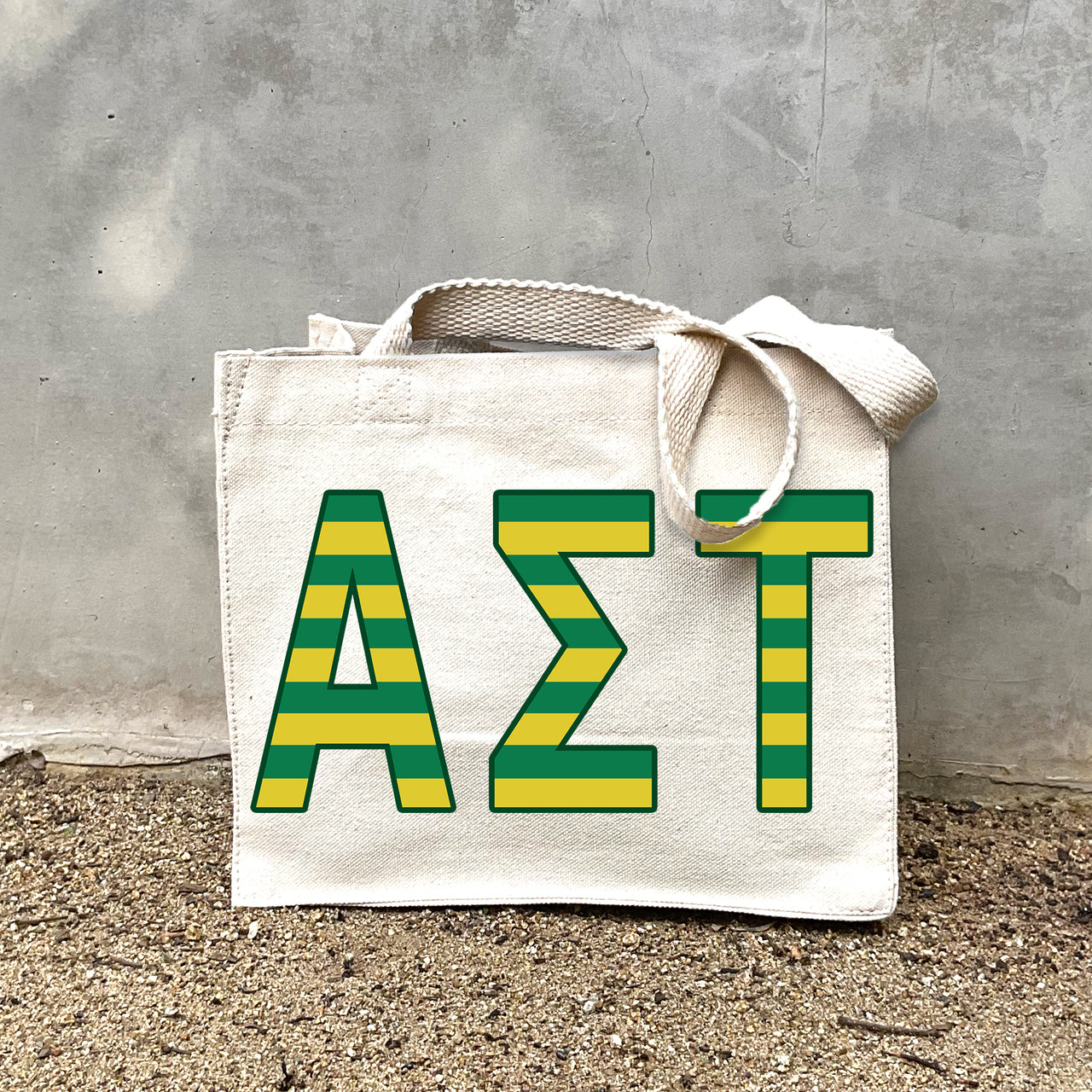 Model carrying the Alpha Sigma Tau Greek letters in sorority colors small striped tote.