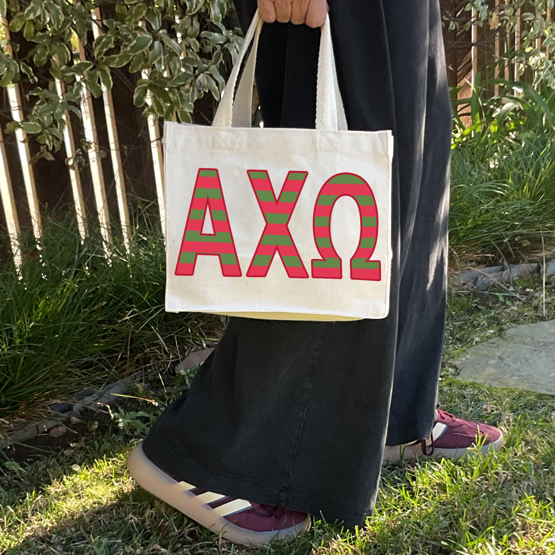 Model carrying the Alpha Chi Omega Greek letters in sorority colors small striped tote.
