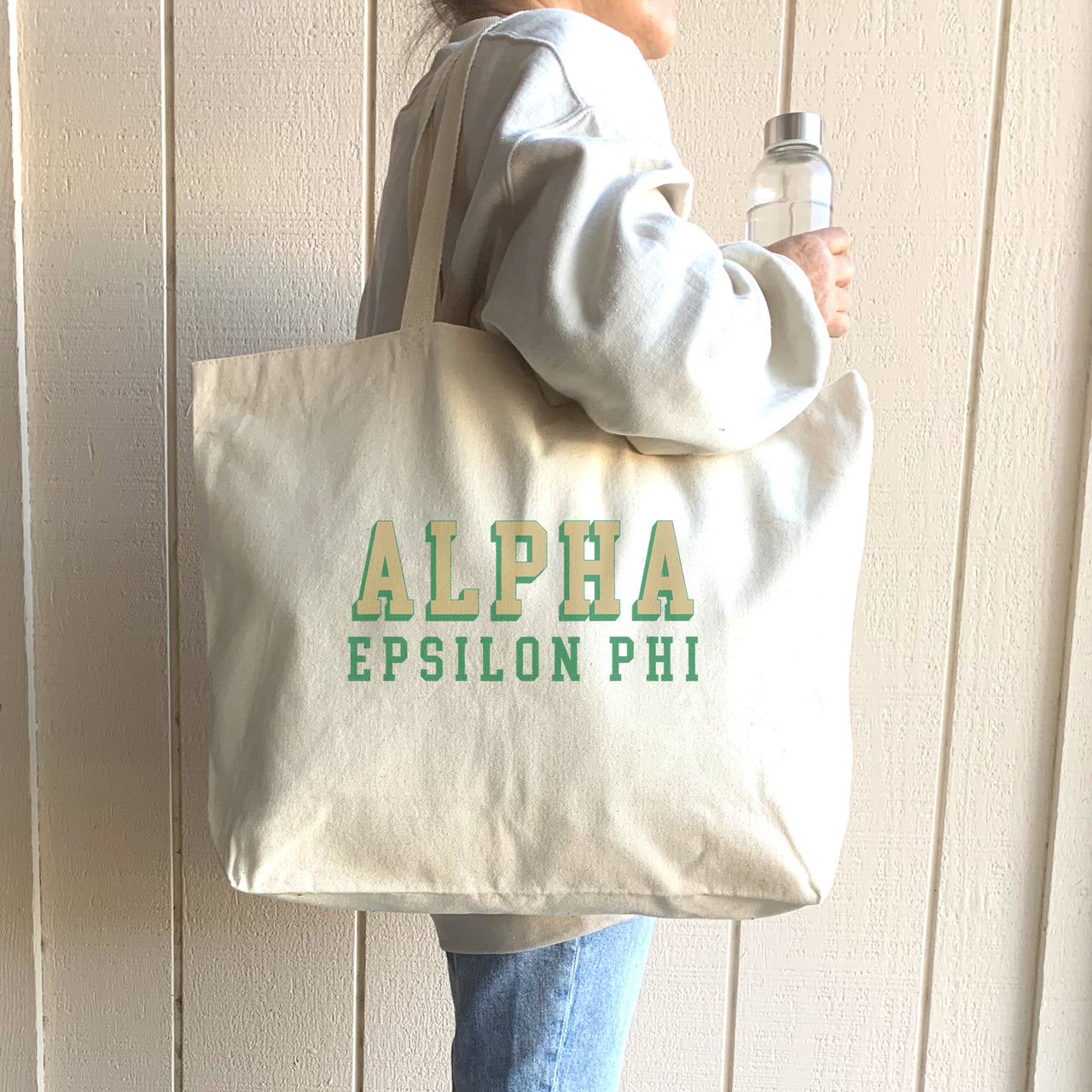 Alpha Epsilon Phi tote bag with dimensional text, shown on the shoulder of a fashionable sorority member.