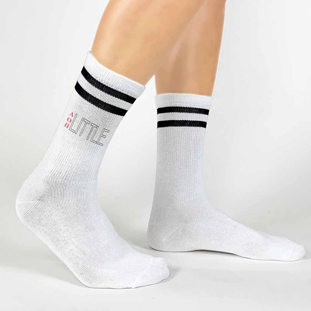 AOP Greek letters printed vertically with a big or little design digitally printed on the outside of both striped cotton crew socks.