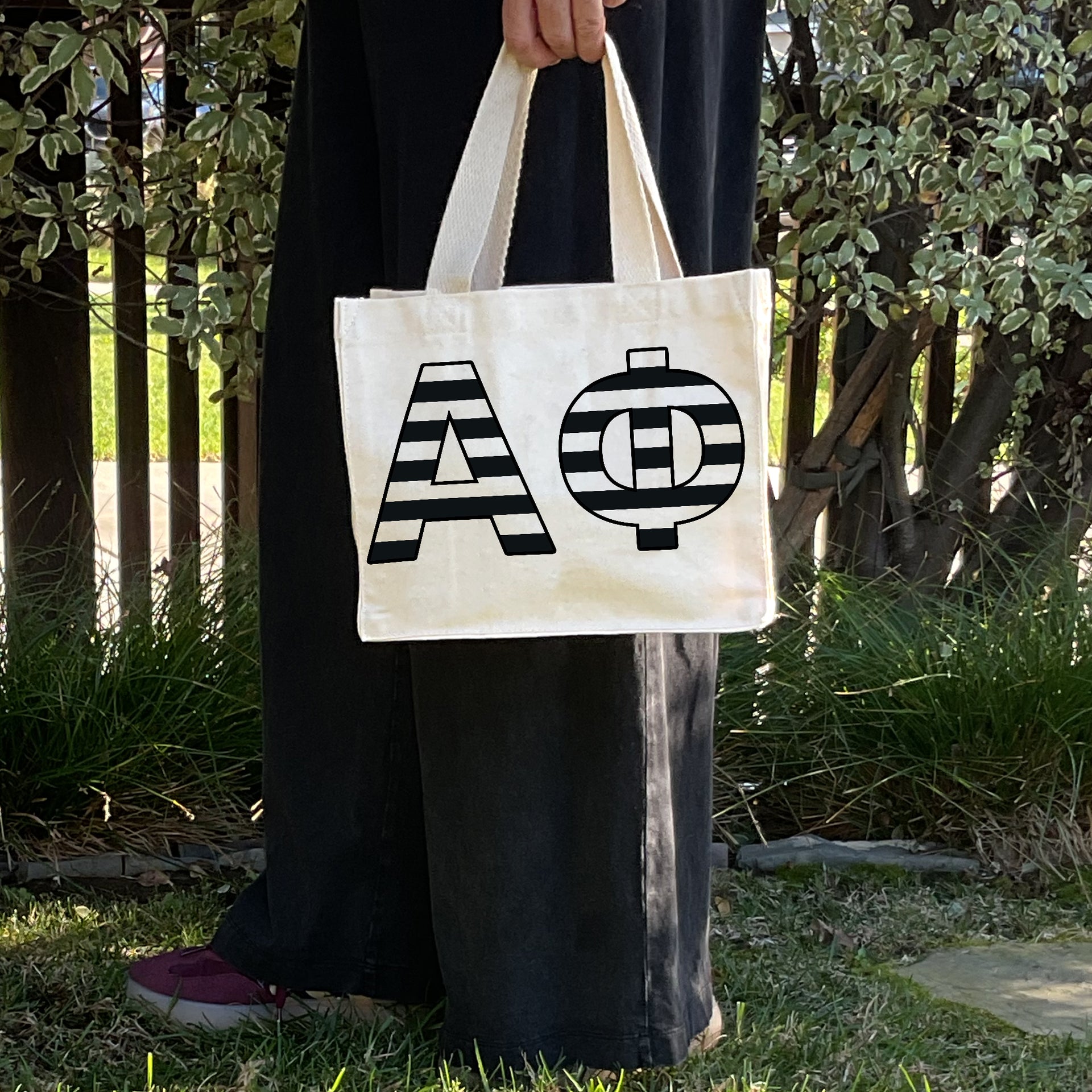 Model carrying the Alpha Phi small black and white stripe tote.