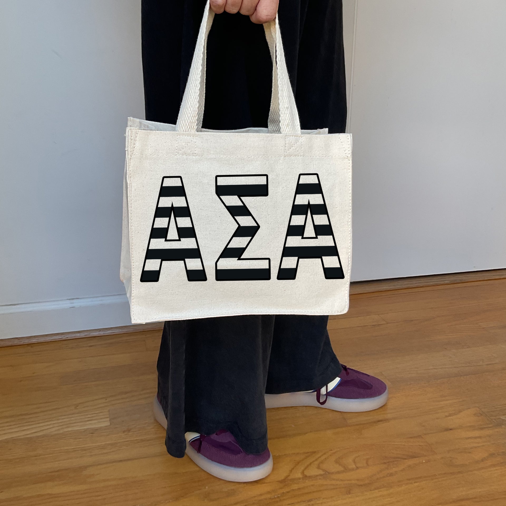 Model carrying the Alpha Sigma Alpha small black and white stripe tote.