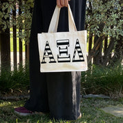 Model carrying the Alpha Xi Delta small black and white stripe tote.