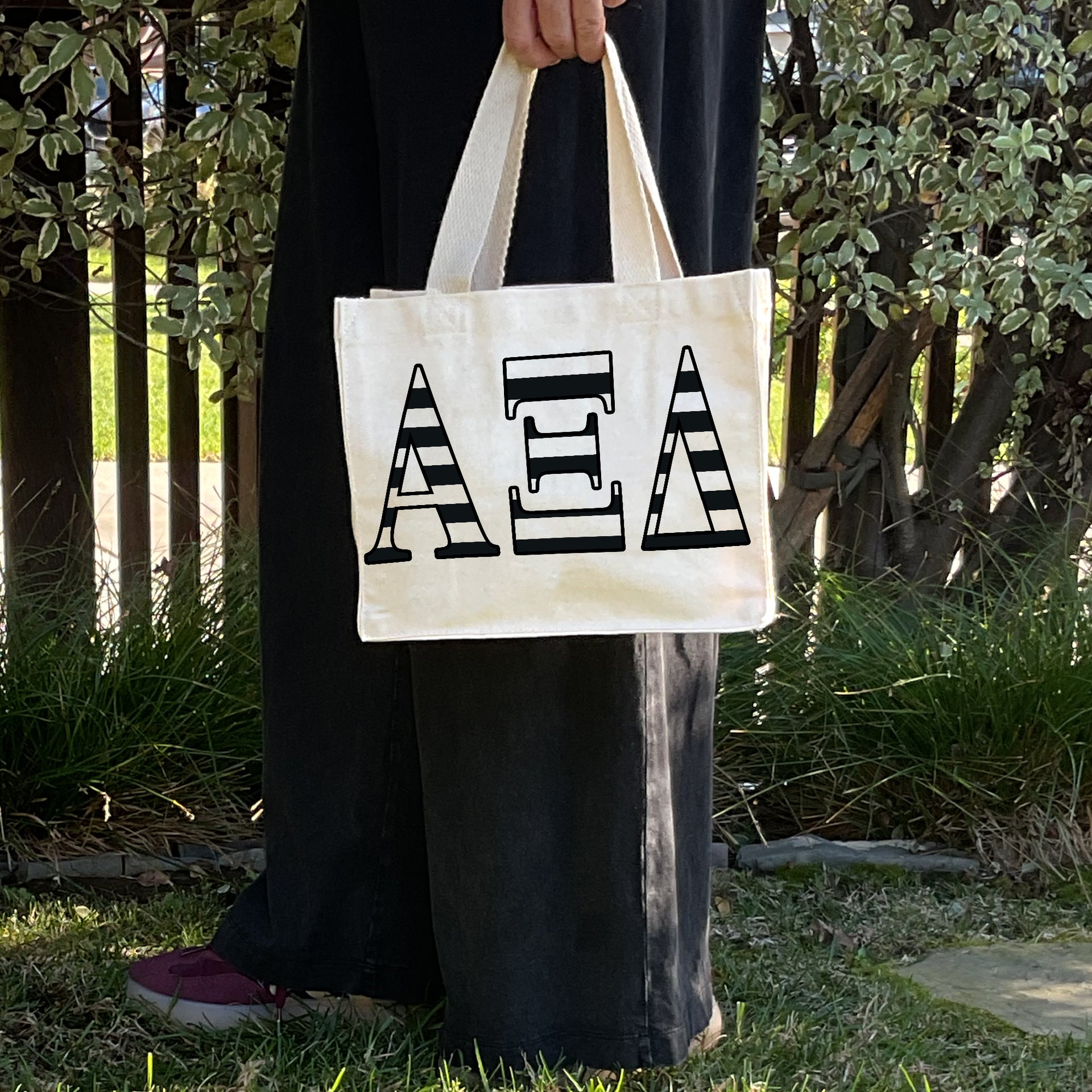 Model carrying the Alpha Xi Delta small black and white stripe tote.