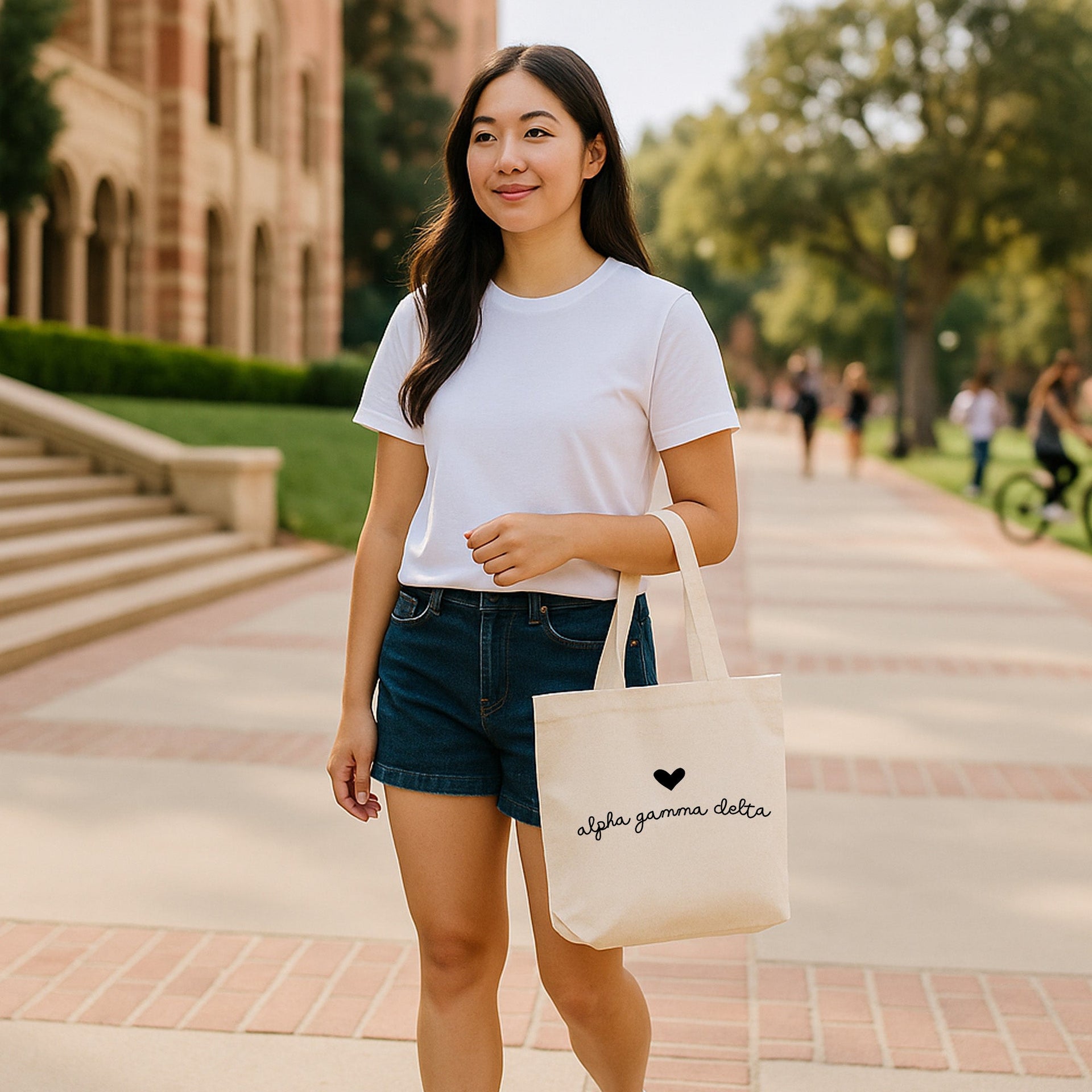 Alpha Gamma Delta sorority tote bag with heart and letters displayed near a chapter house entrance.