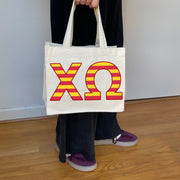 Model carrying the Chi Omega Greek letters in sorority colors small striped tote.