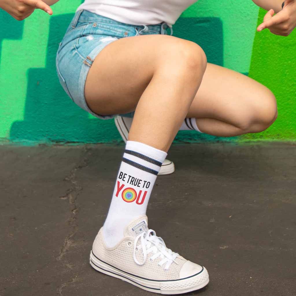 Comfy white cotton crew socks with black stripes custom printed with be true to you rainbow heart design are the perfect accessory for pride month.