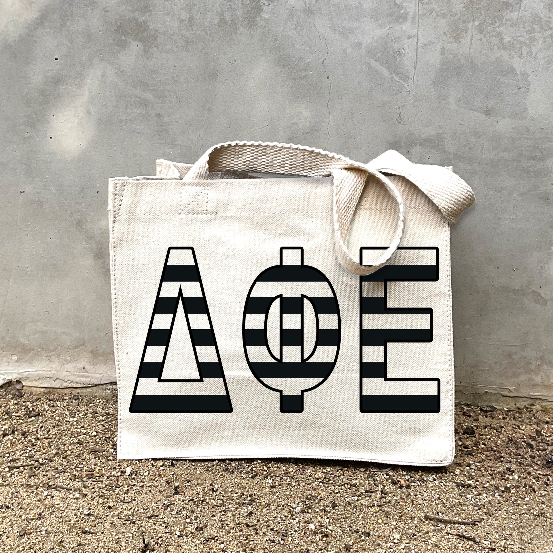 DPE Black Stripe Tote in front of a gray wall