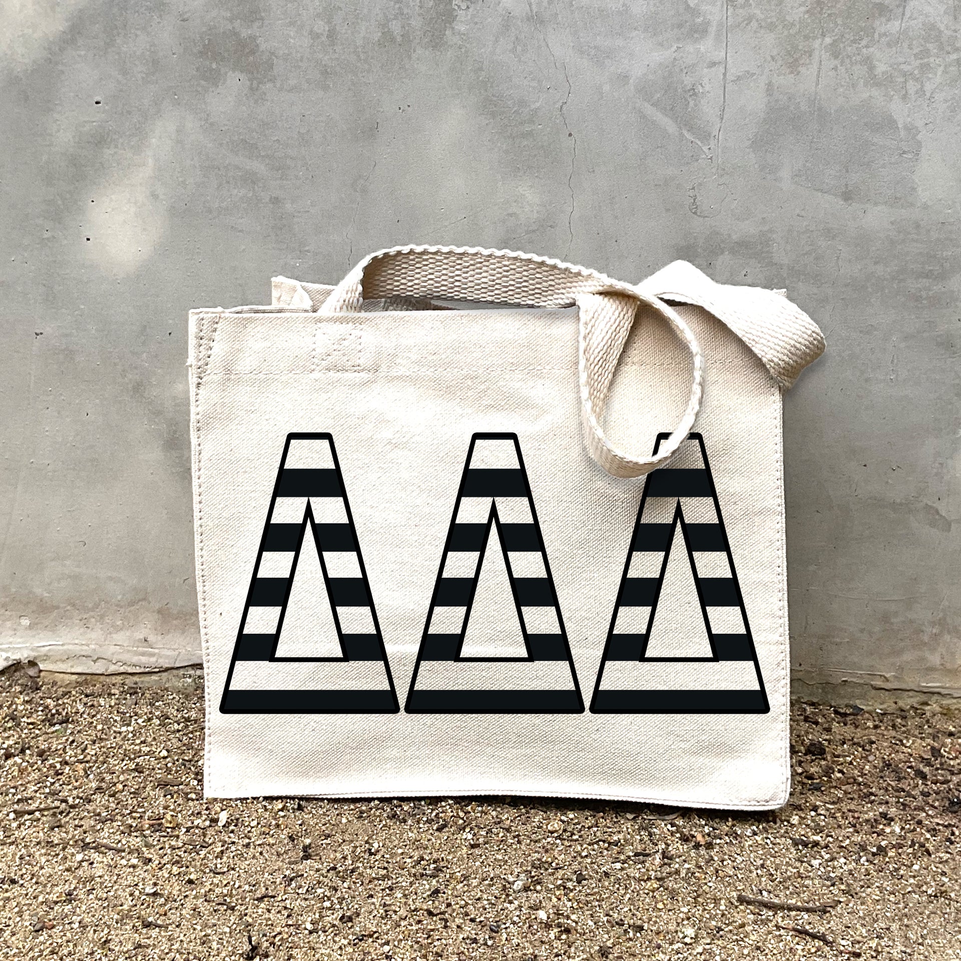 Model carrying the Delta Delta Delta small black and white stripe tote.