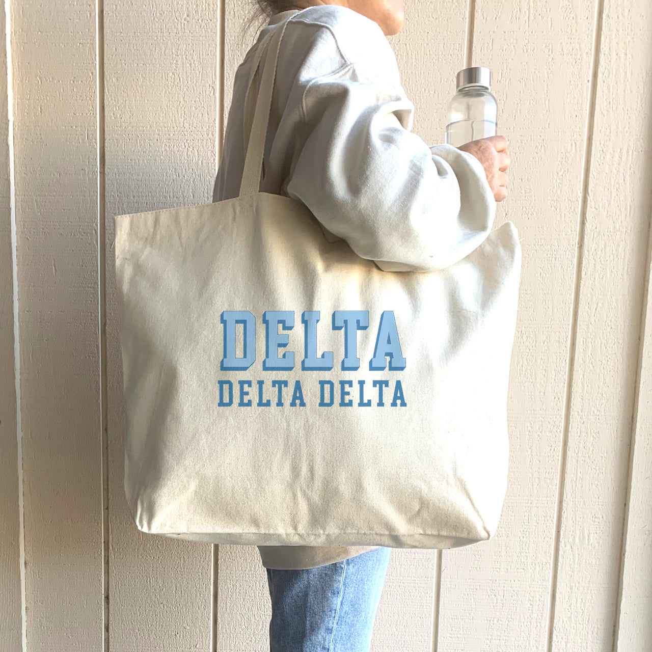 Delta Delta Delta tote featuring 3D name design, carried on the shoulder of a Tri Delta woman.