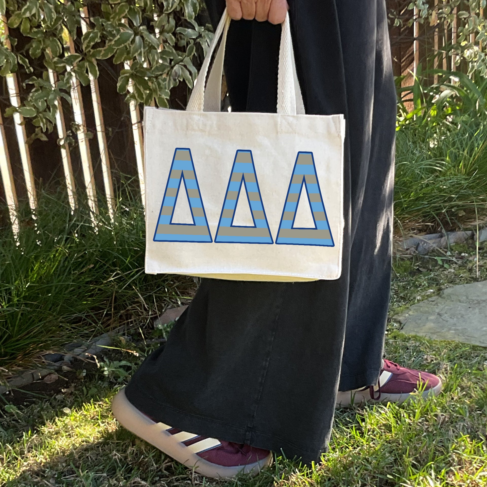 Model carrying the Delta Delta Delta Greek letters in sorority colors small striped tote.