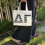 Model carrying the Delta Gamma small black and white stripe tote.