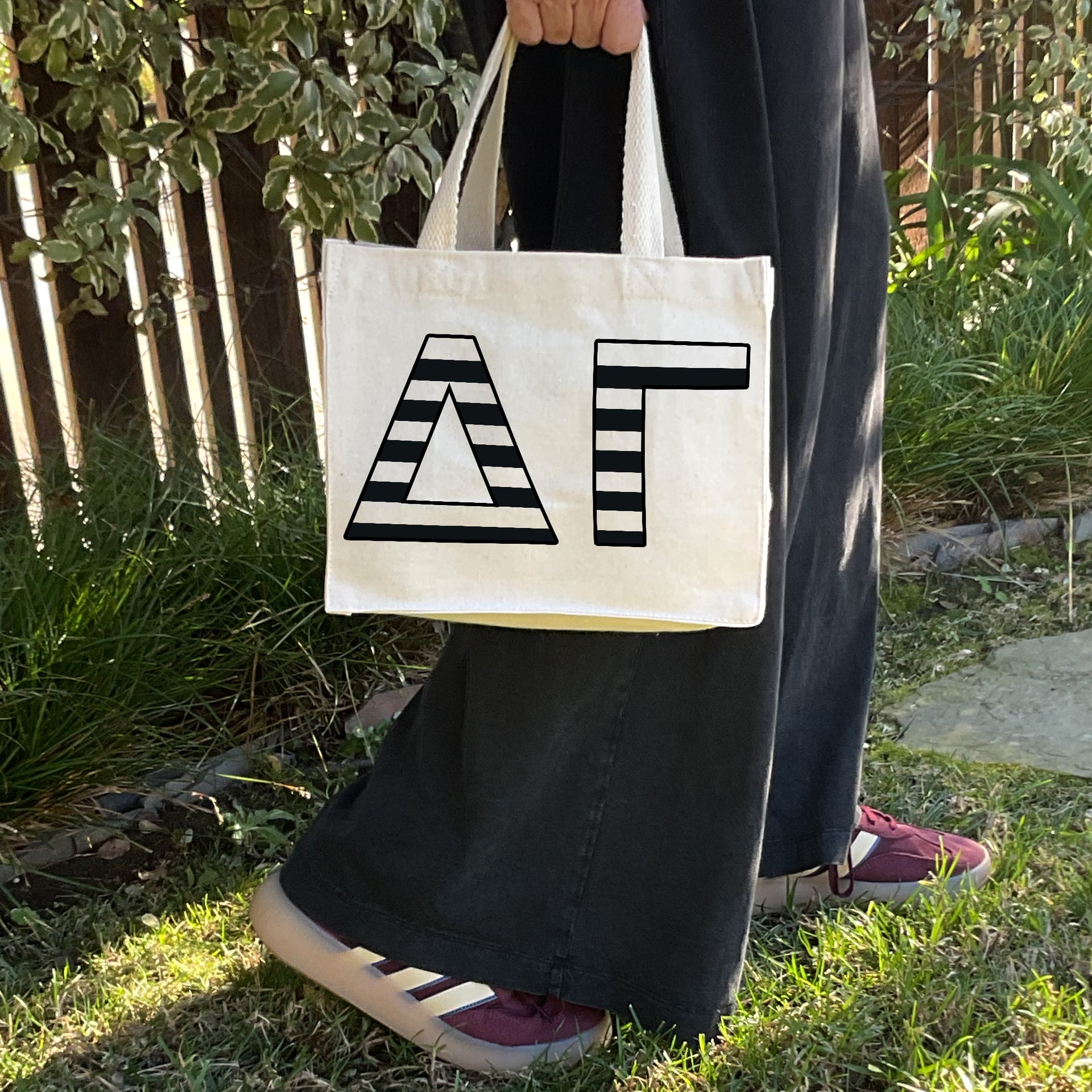 Model carrying the Delta Gamma small black and white stripe tote.