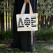 Model carrying the Delta Phi Epsilon small black and white stripe tote.