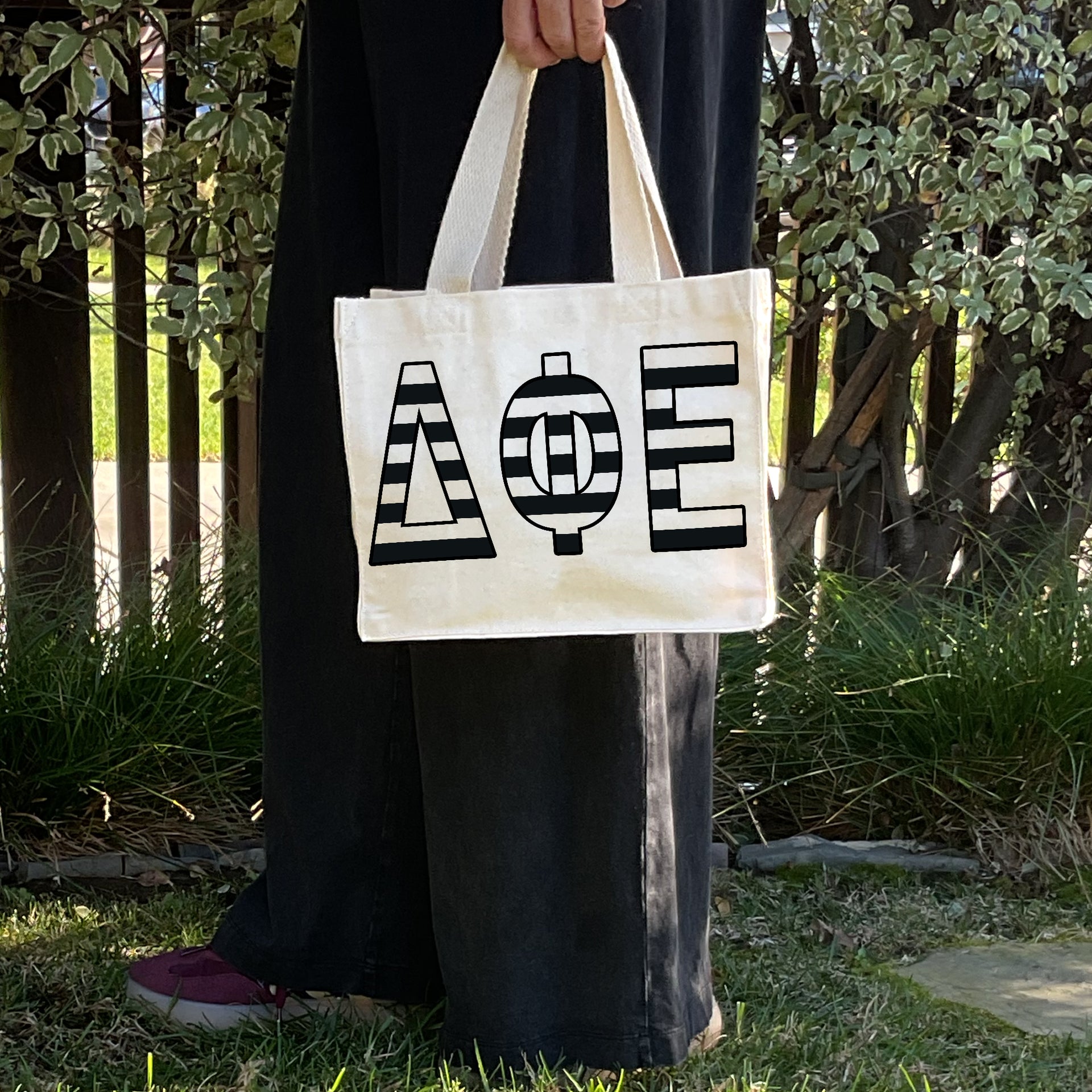 Model carrying the Delta Phi Epsilon small black and white stripe tote.