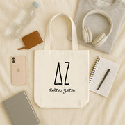 Delta Zeta small canvas tote bag with striped Greek letters styled in a flat lay with everyday essentials