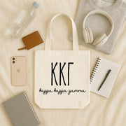 Kappa Kappa Gamma small canvas tote bag with striped Greek letters styled in a flat lay with everyday essentials