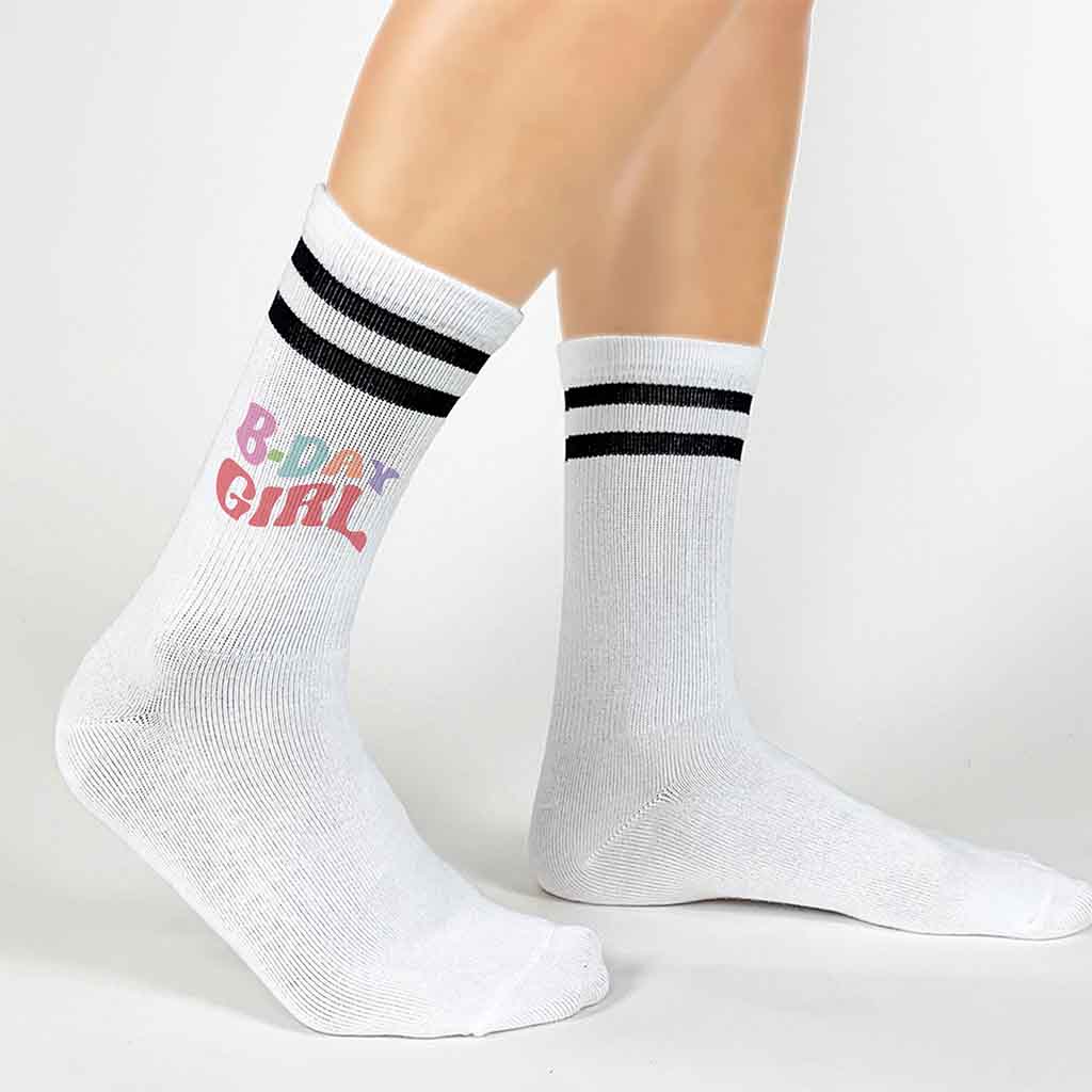 White socks with black stripes digitally printed with B-day Girl on the outside of both socks.