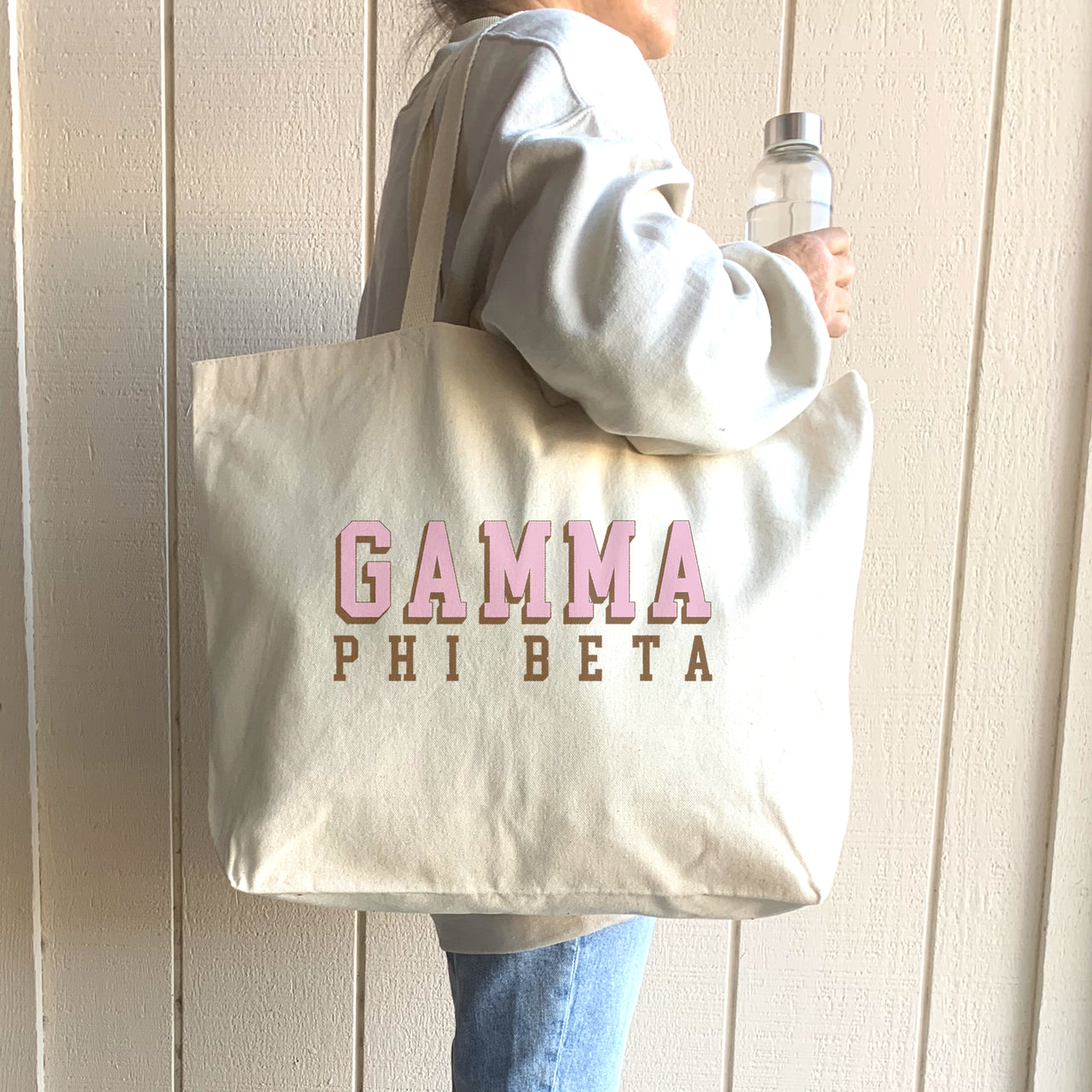 Gamma Phi Beta 3D design tote worn over the shoulder of a Gamma Phi woman in a cozy sweatshirt.