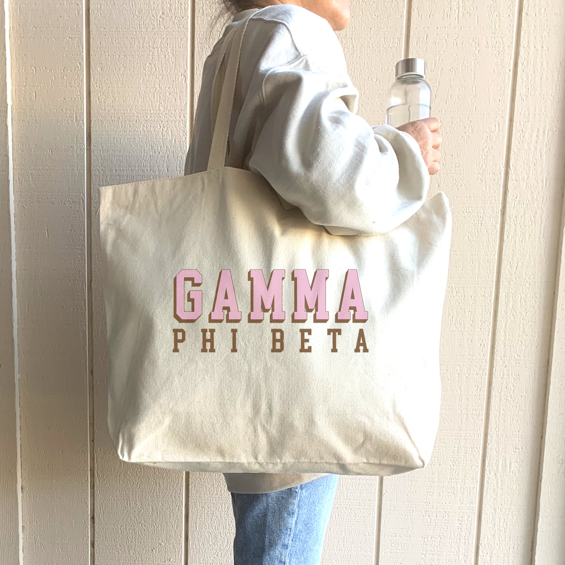 Gamma Phi Beta 3D design tote worn over the shoulder of a Gamma Phi woman in a cozy sweatshirt.