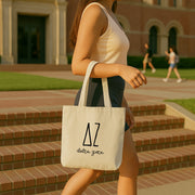 College student carrying a Delta Zeta small canvas tote bag with striped Greek letters