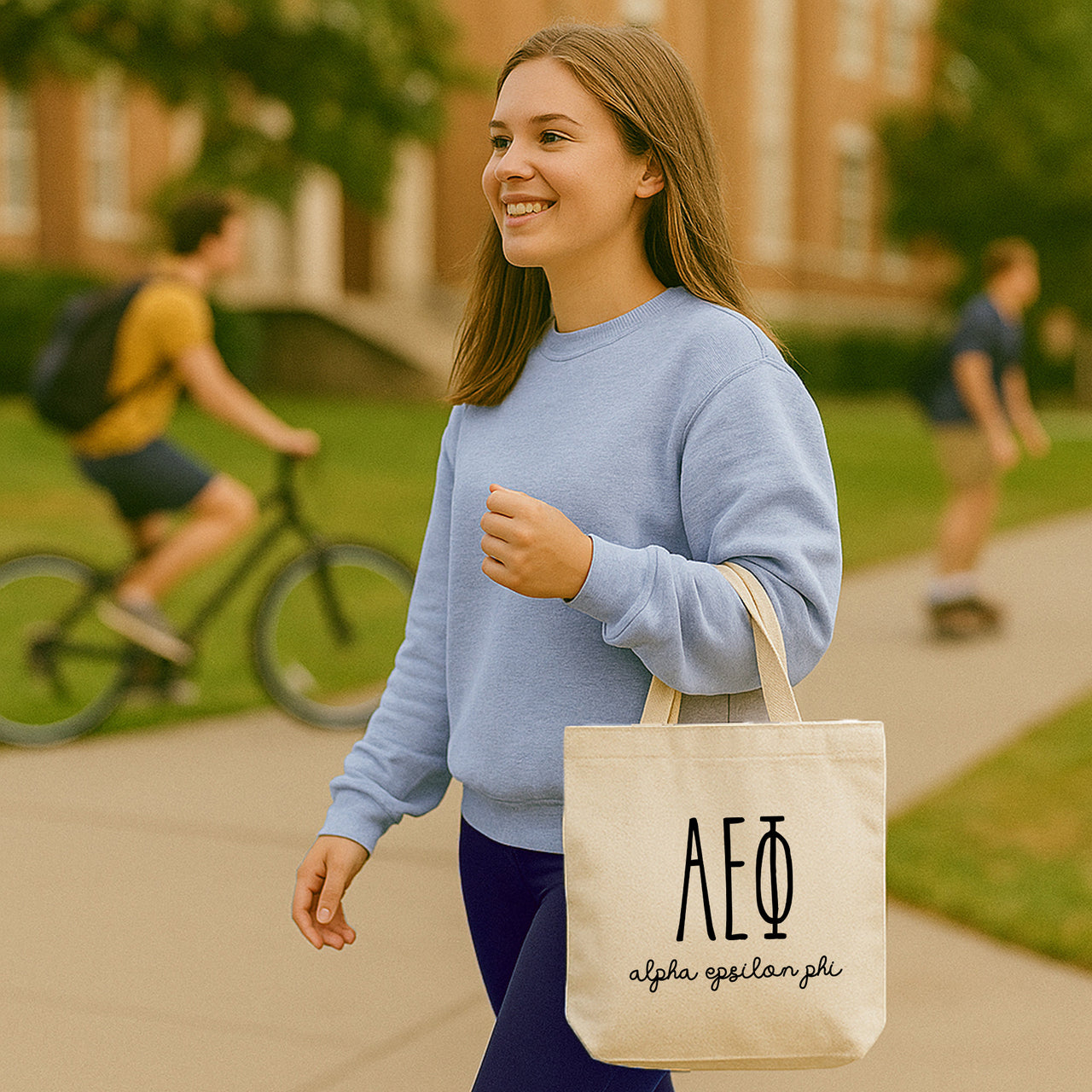 College student carrying an Alpha Epsilon Phi small canvas tote bag with striped Greek letters