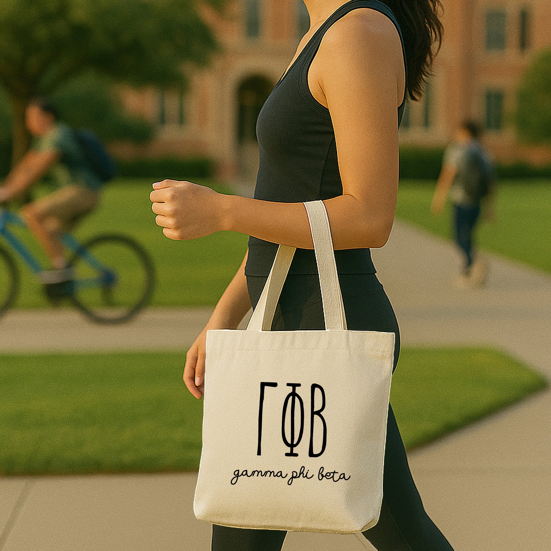 College student carrying a Gamma Phi Beta small canvas tote bag with striped Greek letters