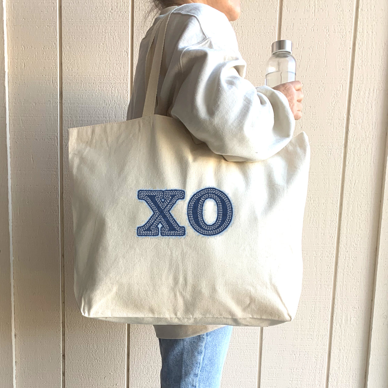 Student wears a denim Chi Omega tote at a sorority recruitment event.