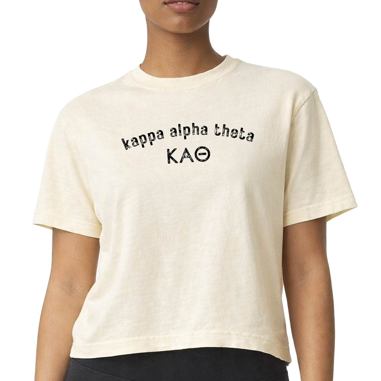 Kappa Alpha Theta woman wearing an officially licensed Comfort Colors boxy crop t-shirt featuring an arched sorority name design with Greek letters