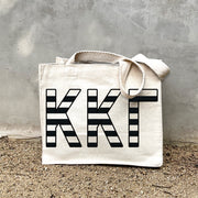 KKG Black Stripe In Black striped letters on a small canvas tote bag