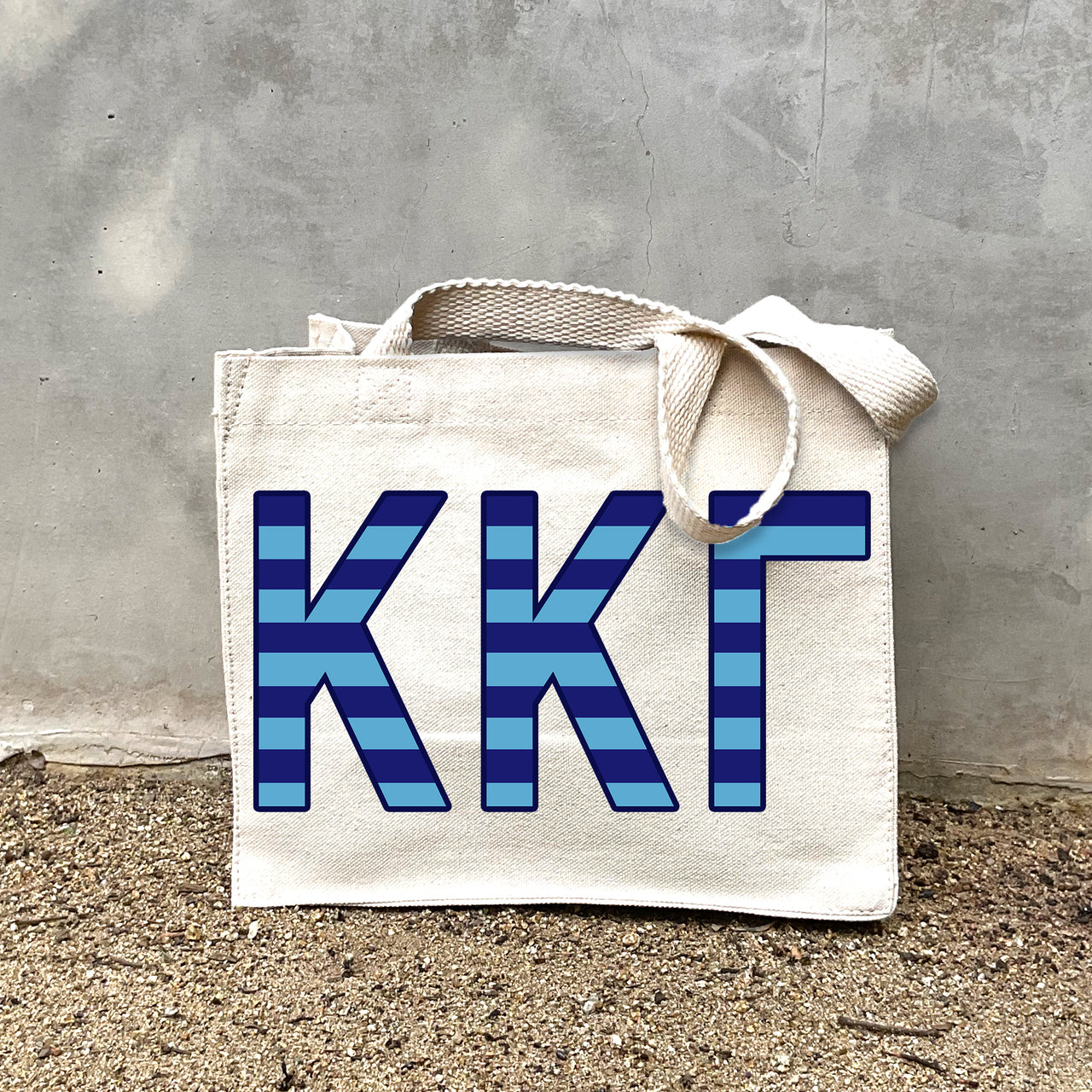 Model carrying the Kappa Kappa Gamma Greek letters in sorority colors small striped tote.