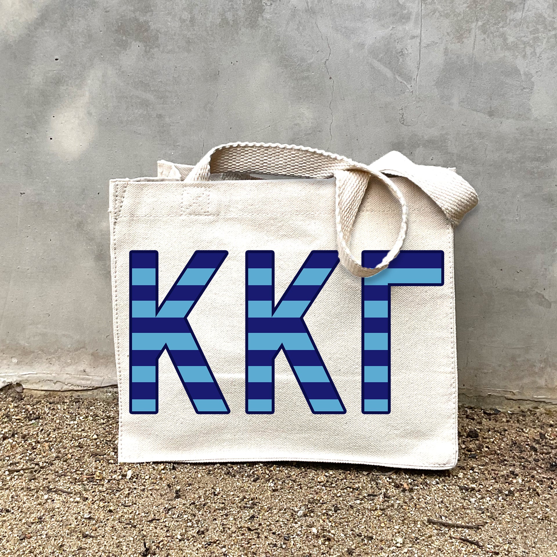 Model carrying the Kappa Kappa Gamma Greek letters in sorority colors small striped tote.