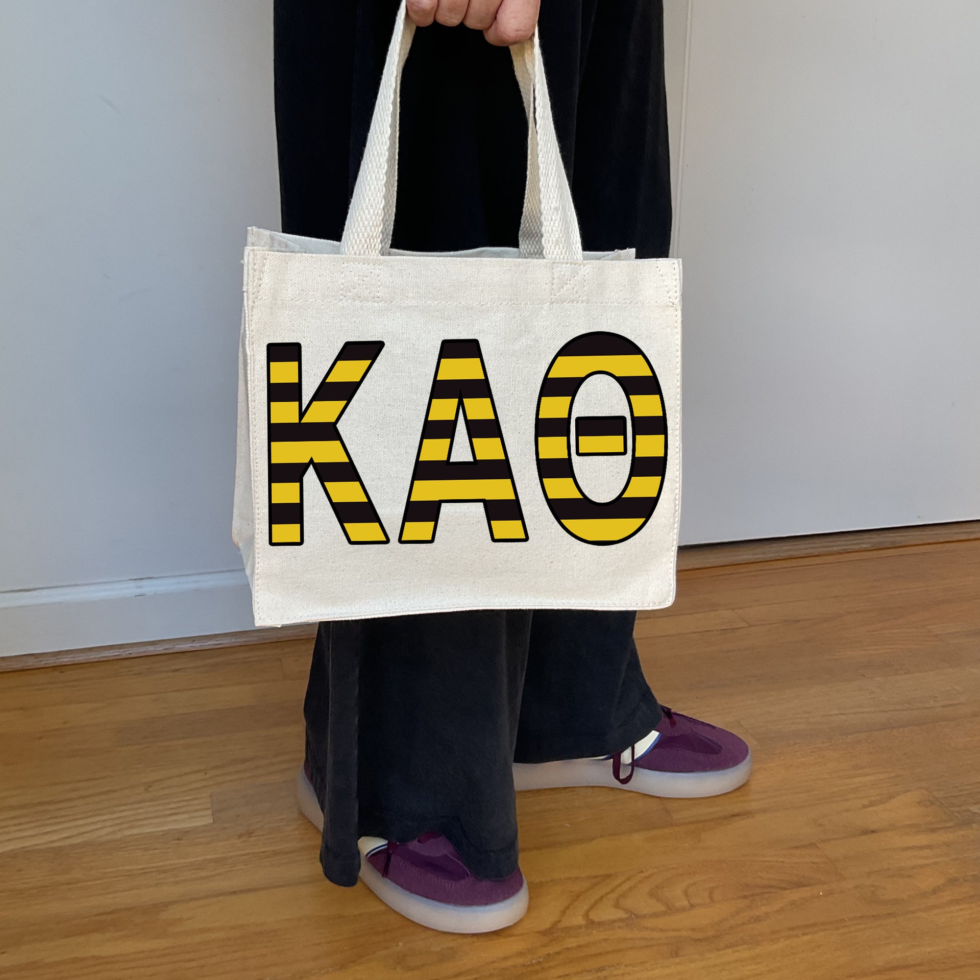 Model carrying the Kappa Alpha Theta Greek letters in sorority colors small striped tote.