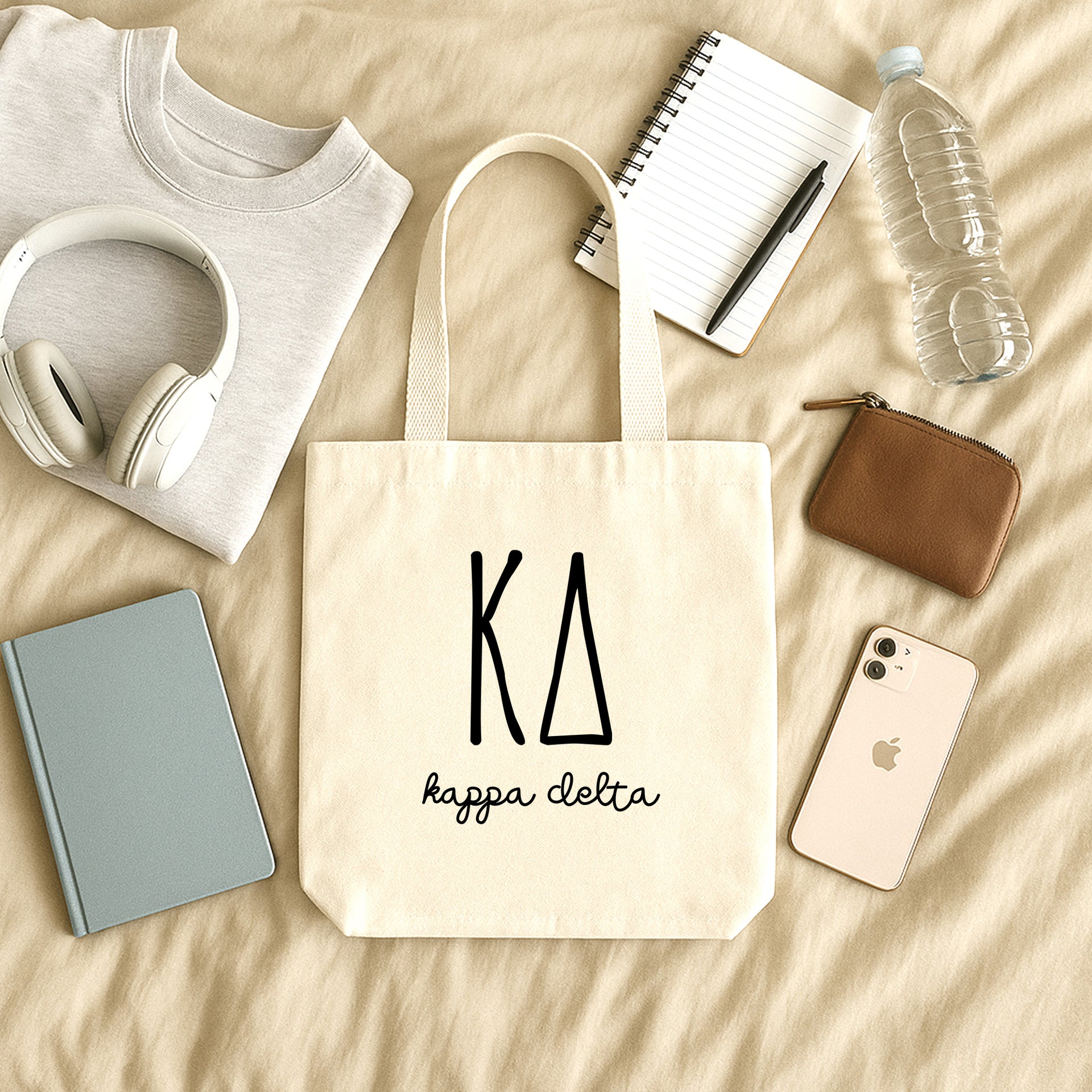 Kappa Delta small canvas tote bag with striped Greek letters styled in a flat lay with everyday essentials