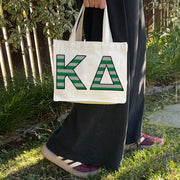Model carrying the Kappa Delta Greek letters in sorority colors small striped tote.