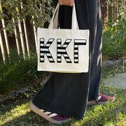 Model carrying the Kappa Kappa Gamma small black and white stripe tote.
