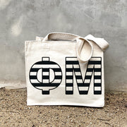 Model carrying the Phi Mu small black and white stripe tote.