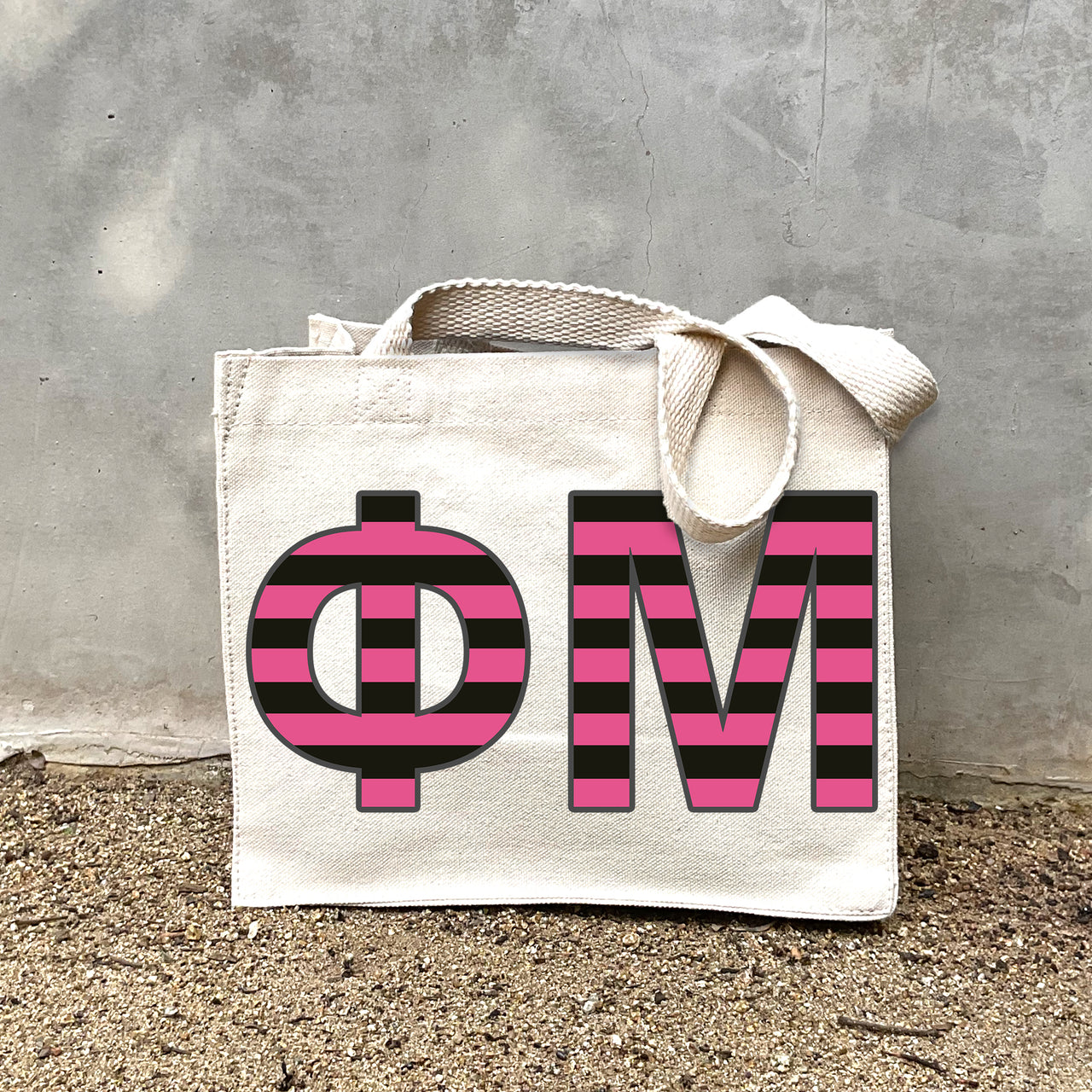Model carrying the Phi Mu Greek letters in sorority colors small striped tote.