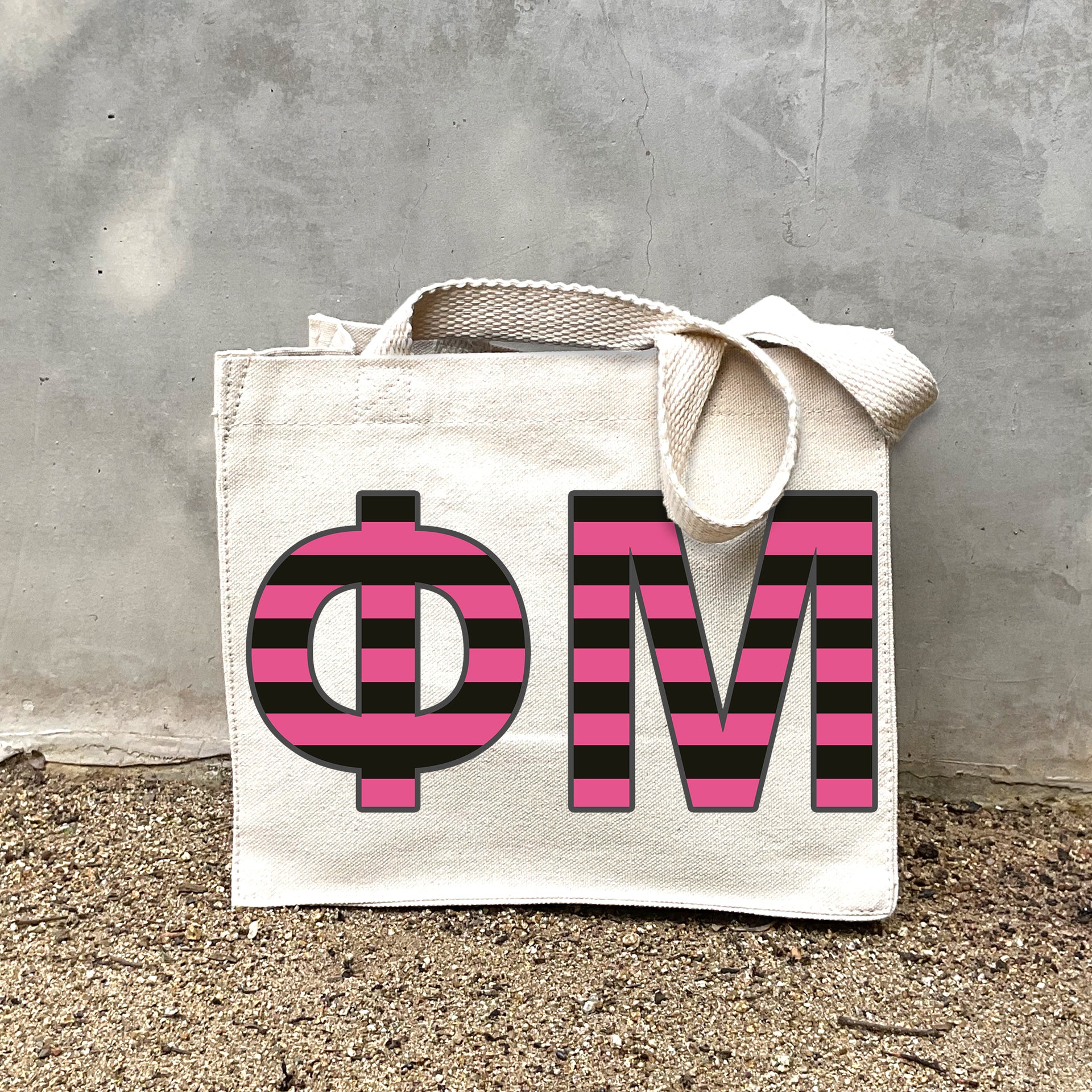 Model carrying the Phi Mu Greek letters in sorority colors small striped tote.