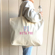 Pi Beta Phi sorority tote with raised name design, carried on the shoulder of a Pi Phi student walking to class.