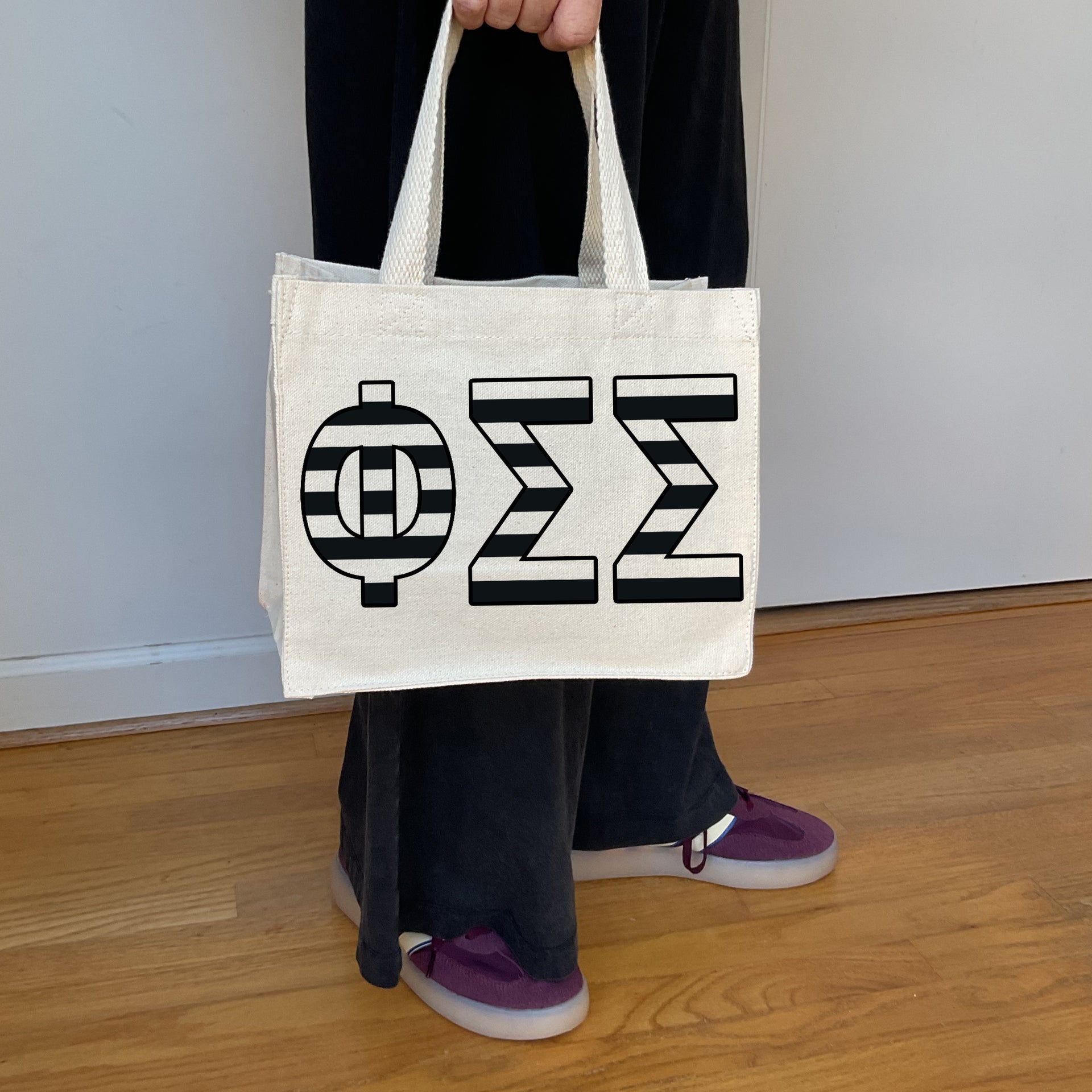 Model carrying the Phi Sigma Sigma small black and white stripe tote.