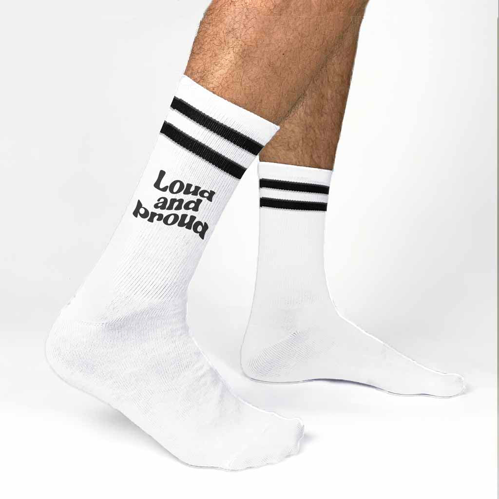 Eye catching socks with an empowering loud and proud design digitally printed in black ink on the side of white cotton crew socks with black stripes.