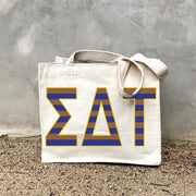 Model carrying the Sigma Delta Tau Greek letters in sorority colors small striped tote.