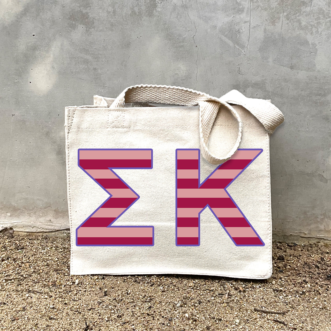 Model carrying the Sigma Kappa Greek letters in sorority colors small striped tote.