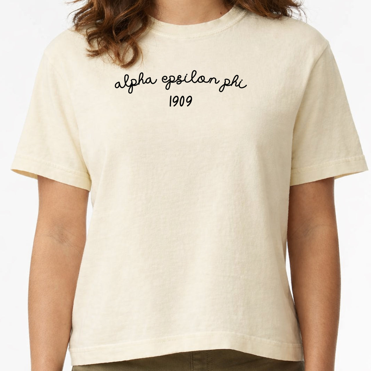 Alpha Epsilon Phi woman wearing an officially licensed Comfort Colors boxy crop t-shirt featuring the sorority name and founding date design