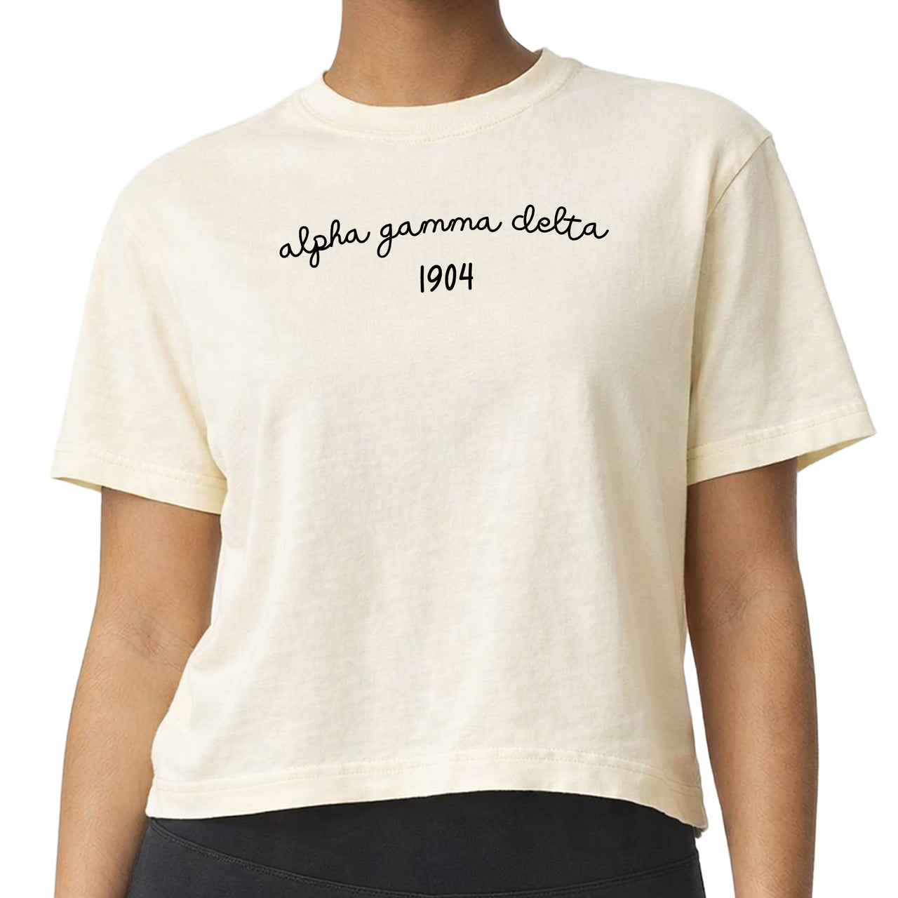 Alpha Gamma Delta woman wearing an officially licensed Comfort Colors boxy crop t-shirt featuring the sorority name and founding date design