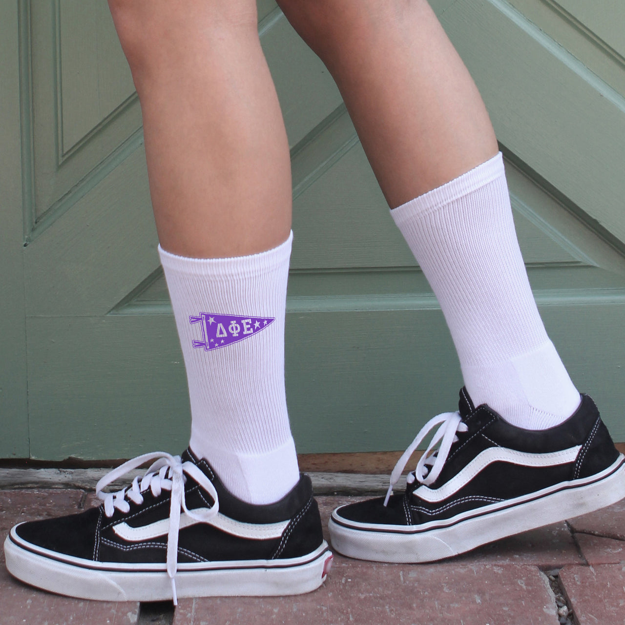 Delta Phi Epsilon sorority member wearing collegiate pennant crew socks featuring DPhiE Greek letters