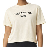Woman wearing a Kappa Alpha Theta Comfort Colors boxy crop t-shirt featuring the sorority name and Greek letters design